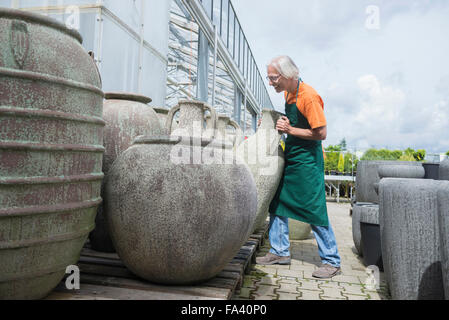 Male gardener arranging ceramic pots in greenhouse, Augsburg, Bavaria, Germany Stock Photo