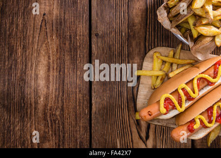 Classic Hot Dog (close-up shot) on wooden background with ketchup and mustard Stock Photo