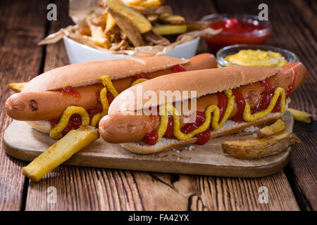 Classic Hot Dog (close-up shot) on wooden background with ketchup and mustard Stock Photo