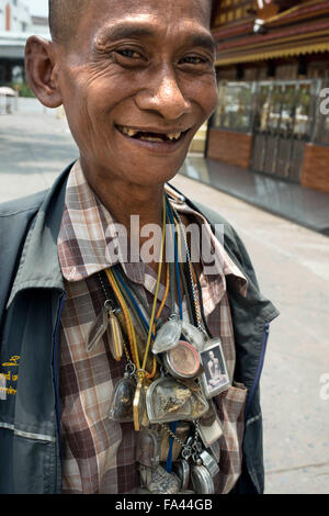 Man loaded down with good luck amulets in Bangkok Thailand. Amulets at the amulet marke, Bangkok, Thailand, Asia. Local religious amulets, charms, talismans & traditional medicines market. Stock Photo