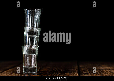Pile of empty shot glasses (close-up shot) on wooden background Stock Photo