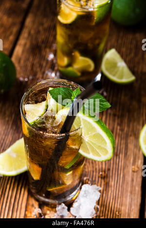 Homemade Cuba Libre with fresh lime, brown rum and crushed ice on an old wooden table Stock Photo