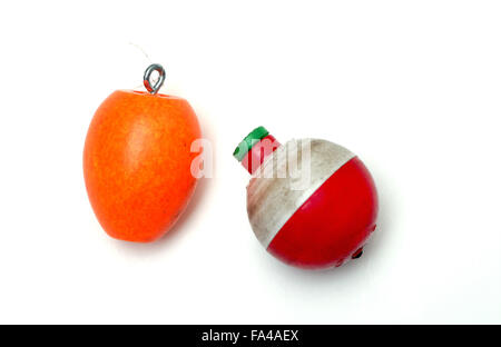 Two fishing bobbers on a white background, one orange and oblong and one round and red and white in color. Stock Photo