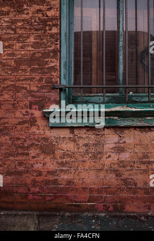 A window with peeling paint on a weathered red brick wall. Stock Photo