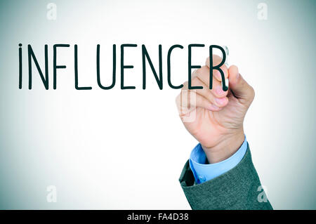 closeup of the hand of a young caucasian man in suit writing the word influencer with a pen in the foreground Stock Photo