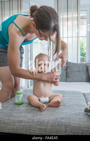 Mother changing her cute son's clothes in bedroom, Munich, Bavaria, Germany Stock Photo