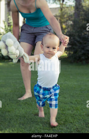 Mother helping her baby boy to take first steps, Munich, Bavaria, Germany Stock Photo