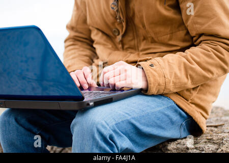 Cropped image of a casual man using laptop computer outdoors Stock Photo