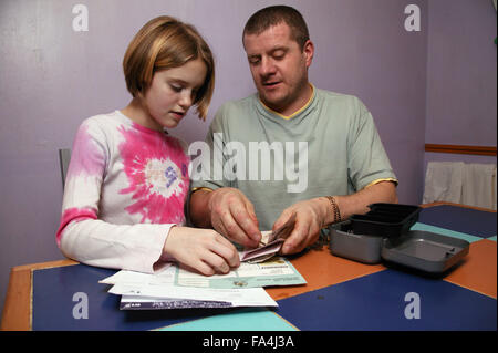 Single parent and young daughter working out bills to pay together and counting money, Stock Photo