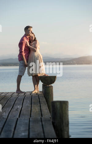 Mature couple standing on pier and looking over lake, Bavaria, Germany Stock Photo