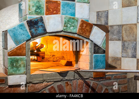 burning fire in professional stone-hearth pizza oven with Italian style tiles Stock Photo