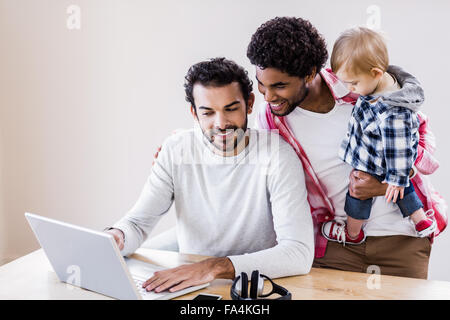 Happy gay couple with child using laptop Stock Photo