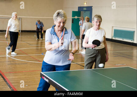 Group of elderly women playing table tennis and badminton in sports hall, Stock Photo