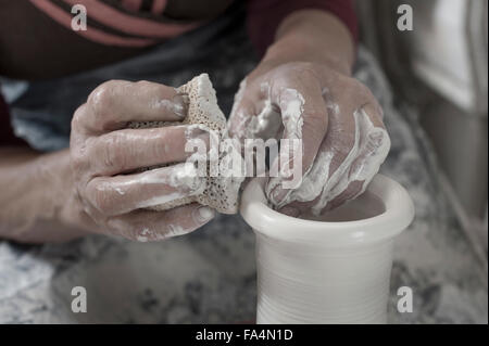 Close-up of female potter moulding clay using cleaning sponge in workshop, Bavaria, Germany Stock Photo