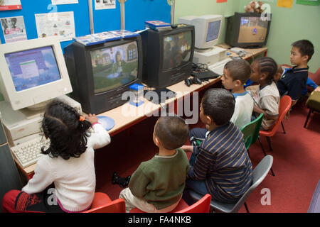 Group of primary school children using computers and watching televisions in classroom,