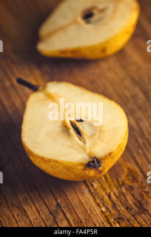 Yellow pear sliced on rustic wooden table, retro toned with copy space Stock Photo