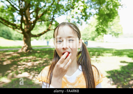 Portrait of a girl eating strawberry in park, Munich, Bavaria, Germany Stock Photo