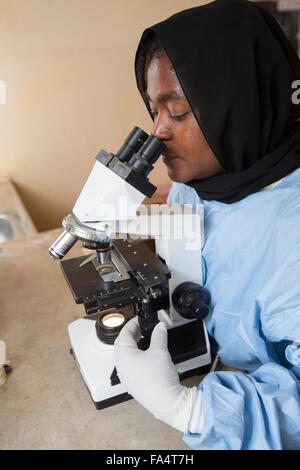 A laboratory assistant operates a microscope at a solar-powered health centre in Kigoma Region, Western Tanzania. Stock Photo