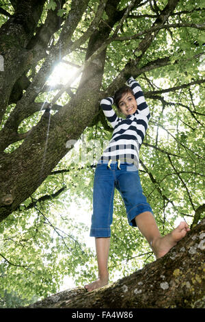 Girl climbing on tree and smiling, Munich, Bavaria, Germany