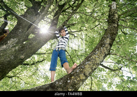 Girl climbing on tree and smiling, Munich, Bavaria, Germany