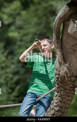 Boy standing on a ship and looking through a telescope in adventure playground, Bavaria, Germany Stock Photo