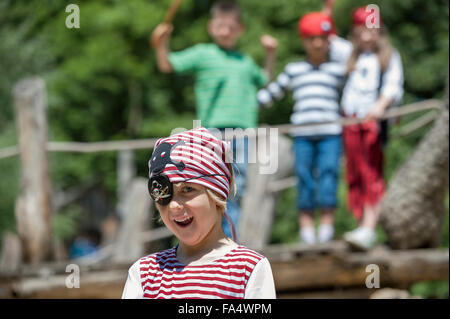 Boy dressed up as a pirate playing in adventure playground with his friends in the background, Bavaria, Germany Stock Photo