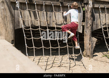 Rear view of a boy climbing on rope in adventure playground, Bavaria, Germany Stock Photo