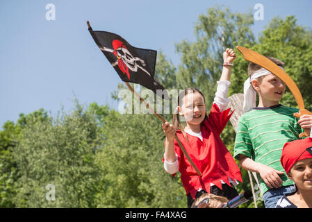Girl holding pirate flag with her friends in adventure playground, Bavaria, Germany Stock Photo