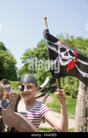 Portrait of a girl dressed up as a pirate holding pirate flag in adventure playground, Bavaria, Germany Stock Photo