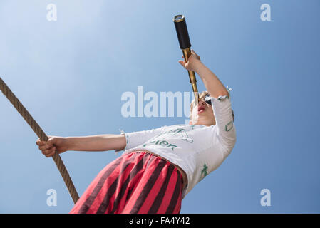 Boy standing on pirate ship in playground and looking through telescope, Bavaria, Germany Stock Photo