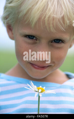 Portrait of young girl holding a daisy.