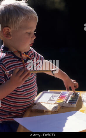 Young boy painting with poster paints. Stock Photo