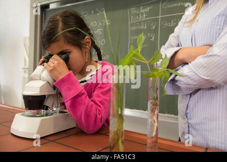 school girl with teacher looking through a microscope, Fürstenfeldbruck, Bavaria, Germany Stock Photo