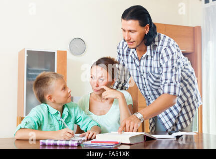 Serious couple with teenager schoolboy doing homework  in home interior Stock Photo