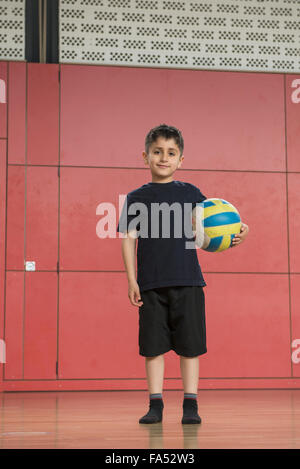 Portrait of a schoolboy holding a ball in sports hall of school, Munich, Bavaria, Germany Stock Photo