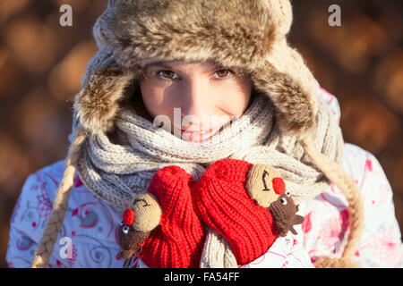 In winter girl in fur hat and mittens looking at the camera Stock Photo