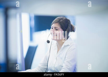 Happy businesswoman wearing headset and working in office, Freiburg Im Breisgau, Baden-Württemberg, Germany Stock Photo