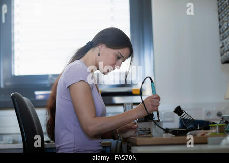 Female technician soldering electronic components in an industrial plant, Freiburg Im Breisgau, Baden-Württemberg, Germany Stock Photo