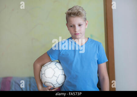 Boy holding football under his arm and looking down, Freiburg im Breisgau, Baden-Württemberg, Germany Stock Photo