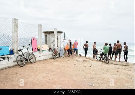 RIO DE JANEIRO, BRAZIL - OCTOBER 22, 2015: Young Brazilian surfers stand looking at incoming waves at Devil's Beach in Arpoador.
