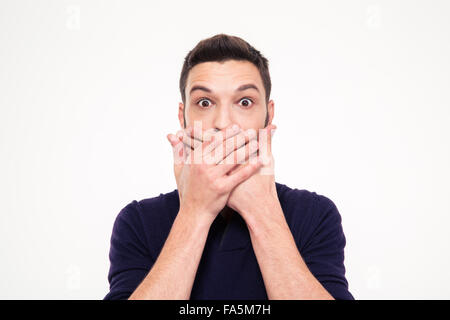 Shocked stunned young man covered mouth by hands over white background Stock Photo