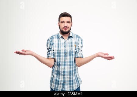 Confused annoyed young man with beard in plaid shirt holding copyspace on palms over white background Stock Photo