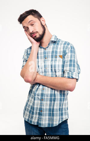 Portrait of sleepy tired handsome young man with beard in plaid shirt standing over white background Stock Photo
