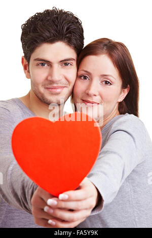Happy young couple in love holding a red heart Stock Photo