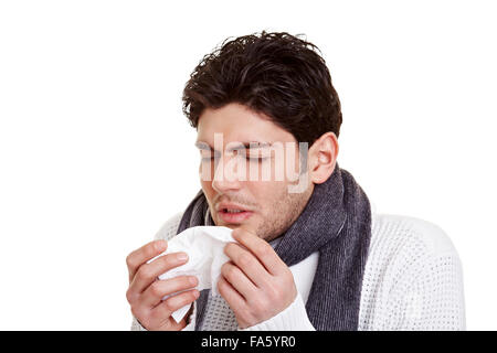 Young man with hay fever sneezing in a tissue