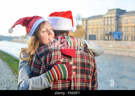 Couple in love hugging outdoors wearing Christmas hats Stock Photo