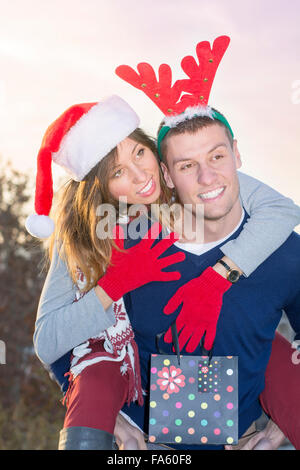 Couple having fun outdoors wearing Christmas holiday hats Stock Photo