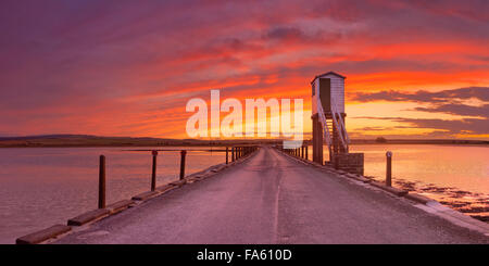 The causeway to Holy Island photographed with a spectacular sunset. At high tide the causeway is impassable, refuge huts on stil Stock Photo