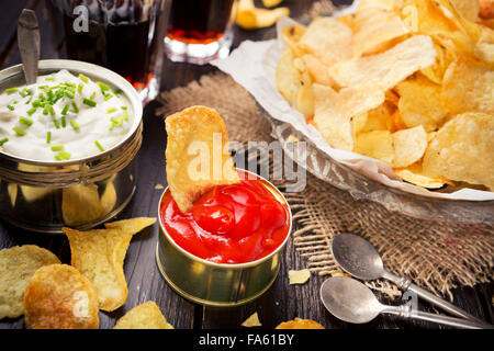 Potato chips with dipping sauces on a rustic table. Stock Photo