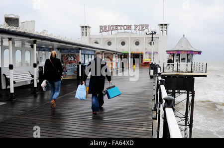 Brighton Sussex UK 22nd December 2015 - These Christmas shoppers take a break and head on to the pier in the wet and windy weather conditions on Brighton seafront today  Credit:  Simon Dack/Alamy Live News Stock Photo